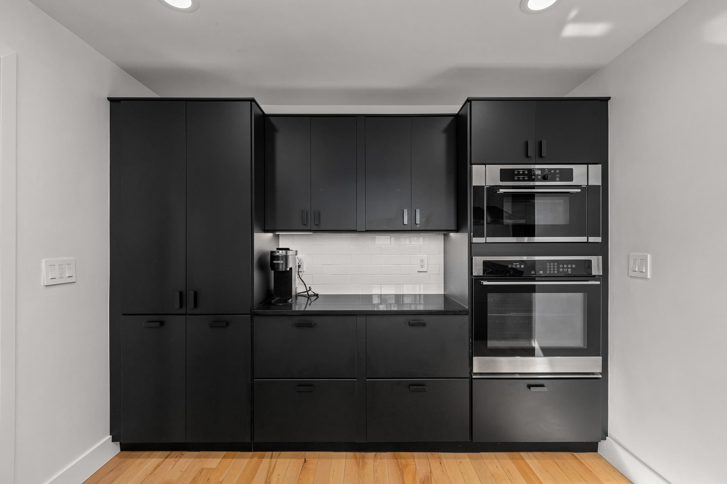 Black pantry cabinetry and stacked appliance wall